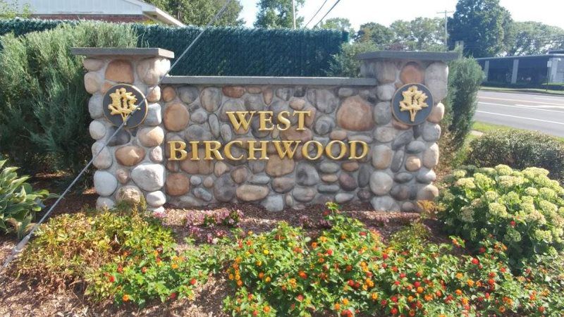 Mineola Monument Pylon Signs
A sophisticated stone monument sign with golden lettering, set against a natural stone wall at the entrance of a residential community.
The West Birchwood stone monument sign exudes elegance and durability, making it a pe